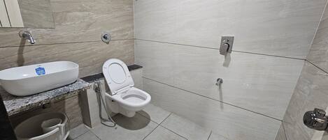 Un baño con lavamanos, inodoro y ducha blancos.