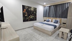 A modern bedroom with a bed, bedside tables, a TV, and a large window with a jungle-themed artwork. - HOTEL ROYAL VIEW (Ahmedabad)