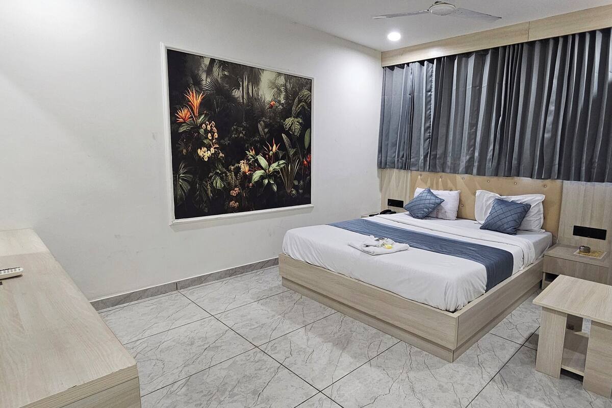 Quarto moderno com cama, mesas de cabeceira, televisão e uma grande janela com uma obra de arte com tema de selva.
