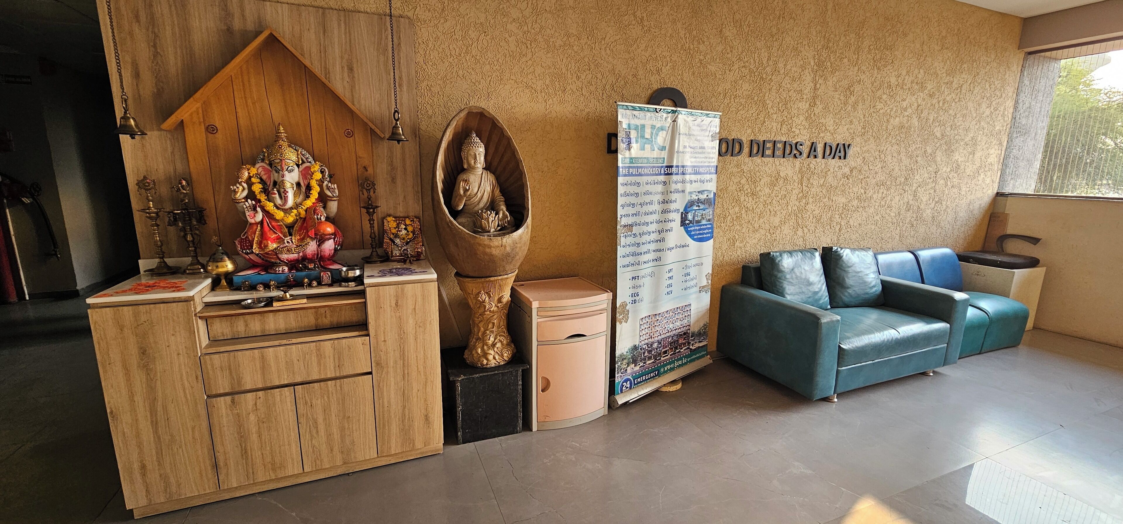 Un espace d’accueil comprenant un bureau en bois, une statue, un canapé et un mur sur lequel est affiché un panneau.