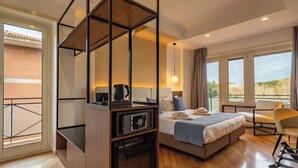 A modern hotel room with a bed, a desk with a coffee maker, a chair, and a view of the outdoors. - Relais Pamphili guest house by Ghor (Rome)