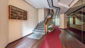 A hallway with a red carpet, wooden flooring, a staircase with a wooden handrail, and a wall-mounted bookshelf. - Relais Pamphili guest house by Ghor (Rome)