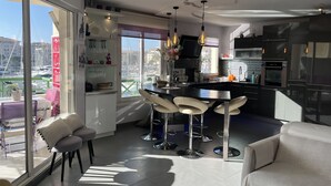 Eine moderne Küche mit Kochinsel, Barhocker und Essbereich mit einer Couch und Stühlen.