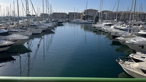 Ein Yachthafen mit zahlreichen angestückten Booten, ruhigem Wasser und Gebäuden im Hintergrund.