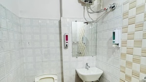 Un baño pequeño con inodoro, lavamanos y calentador de agua montado en la pared.
