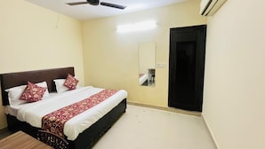 Una habitación de hotel con una cama, ventilador de techo, equipo de aire acondicionado y una puerta.