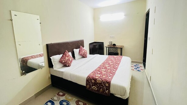 Un dormitorio con cama, espejo, ventilador de techo y una pequeña mesa con silla.