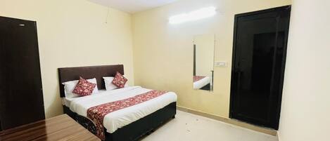 Une chambre à coucher avec un lit, un bureau, un ventilateur de plafond et une porte.