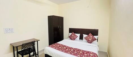 A bedroom with a bed, a desk, a wardrobe, and a ceiling fan.