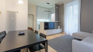 Ett modernt vardagsrum med en matplats, en platt-TV och en soffa.