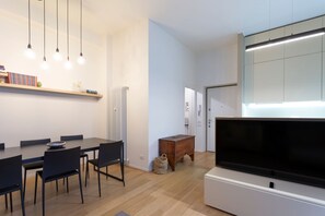Un salon moderne comprenant un coin repas, un téléviseur à écran plat et un radiateur.