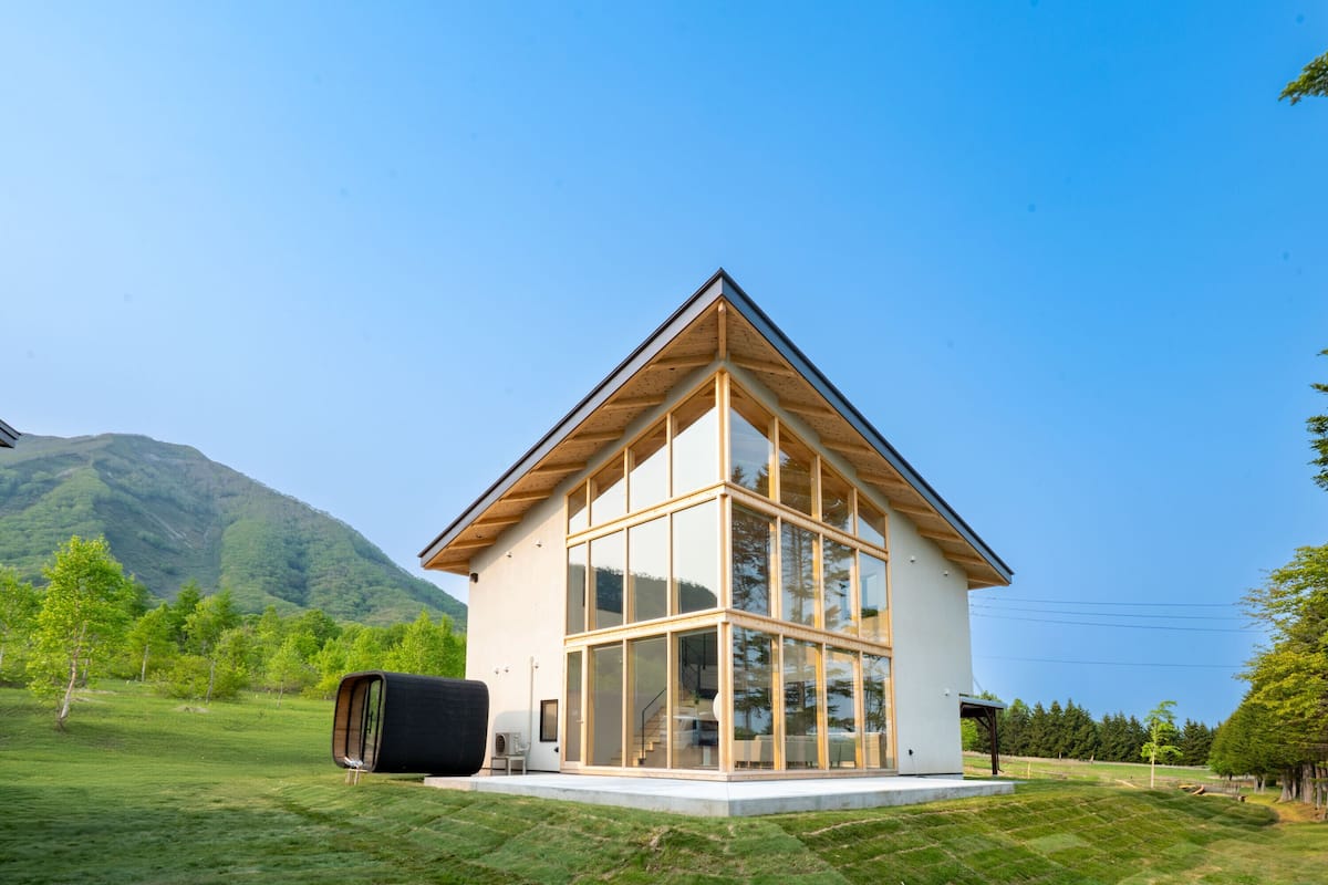A modern house with a triangular roof, large glass windows, and a wooden exterior.