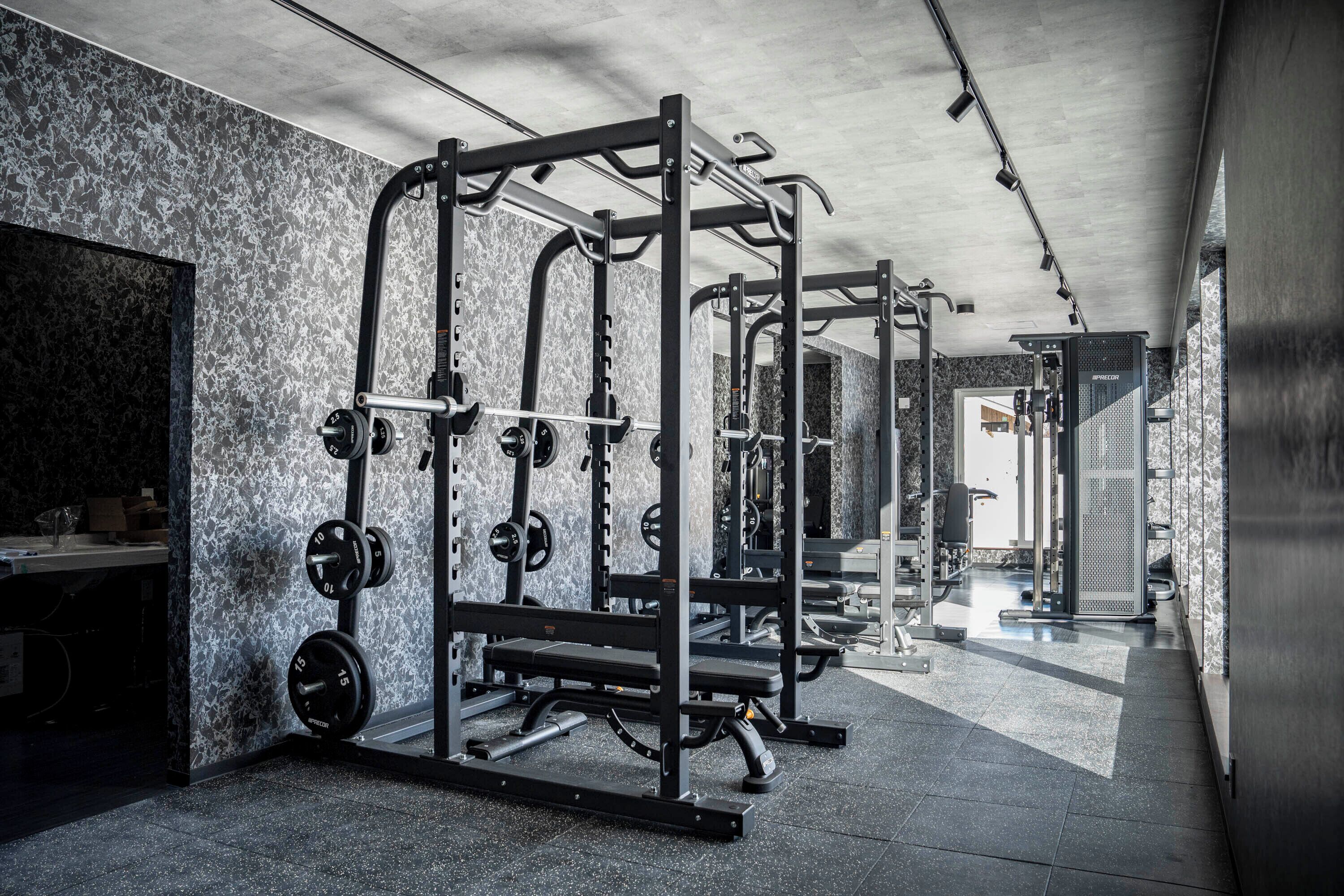 A gym with weightlifting equipment and a mirrored wall.