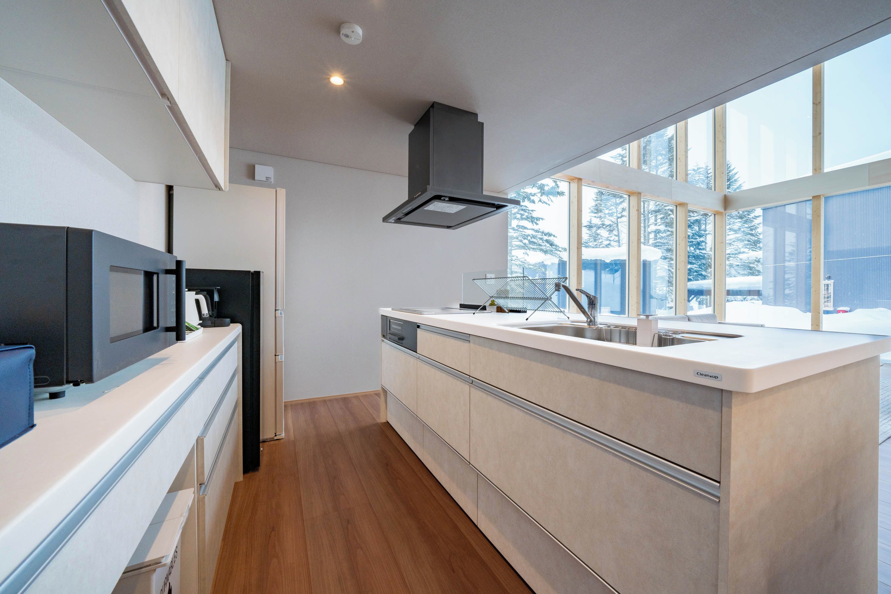 A modern kitchen with a built-in microwave, a dishwasher, and a large window providing a view of the outdoors.