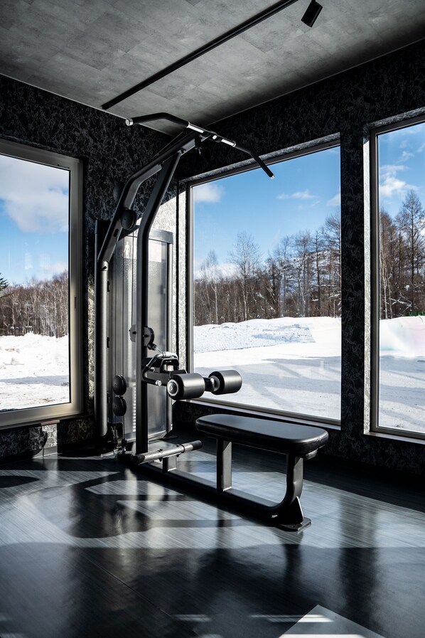A gym with exercise equipment, large windows, and a view of a snowy landscape.