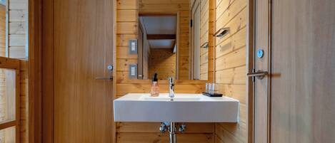 A wooden-paneled bathroom with a white sink, a mirror, and a door.