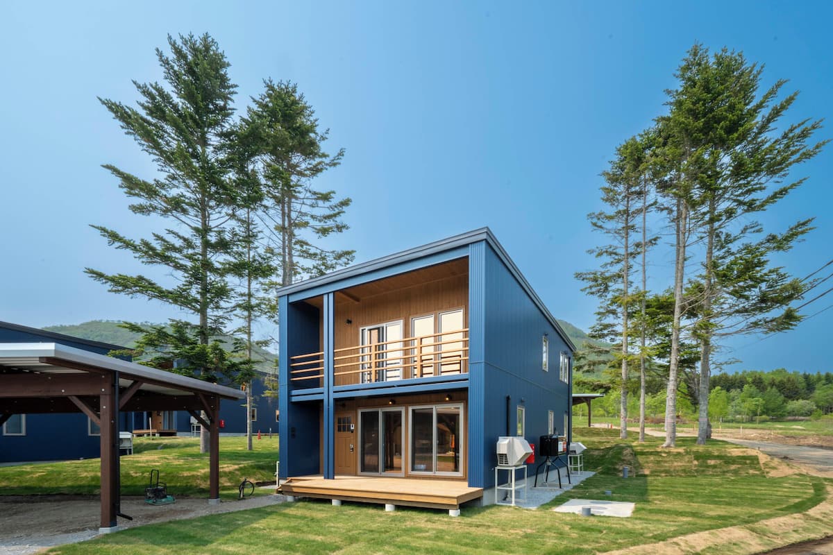 A modern two-story house with a wooden deck and a covered patio area.