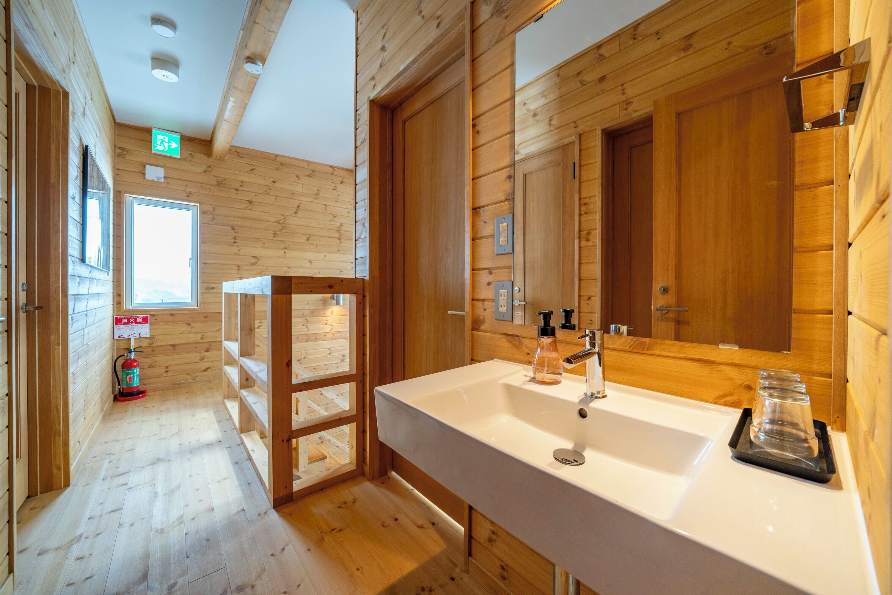 A wooden cabin bathroom with a large sink, wooden walls, and a window.