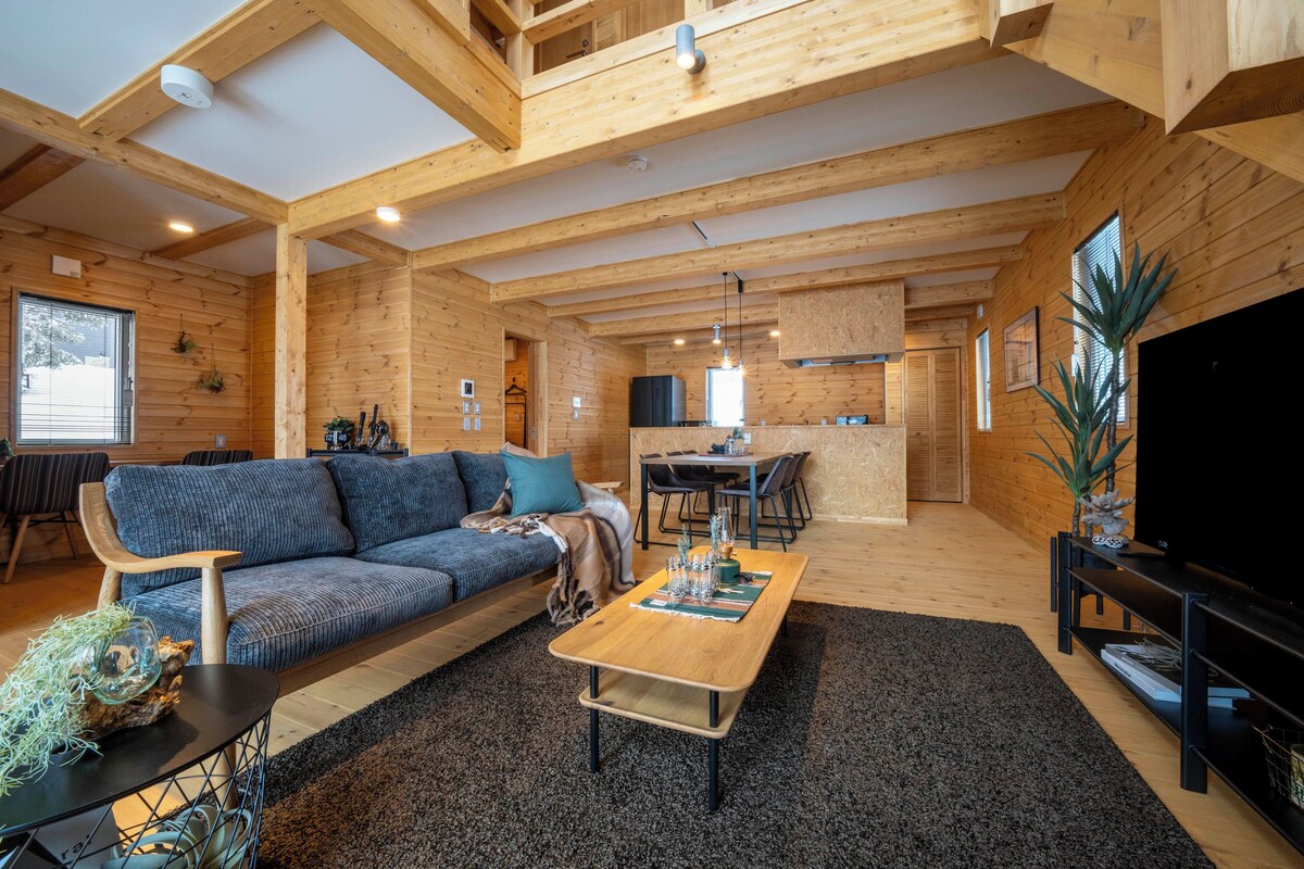 A modern living room with a wooden ceiling, a sofa, a coffee table, and a TV.