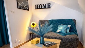 A cozy living room with a teal sofa, a coffee table, and a blue rug. - Cosy studio in the center of town (Redon)