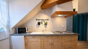 A kitchen with a microwave, sink, and wooden cabinets. - Cosy studio in the center of town (Redon)