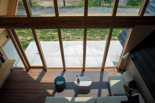 A room with a large skylight, wooden beams, a white sofa, a small round table, and a blue chair. - ERUSA RUSUTSU (Rusutsu)