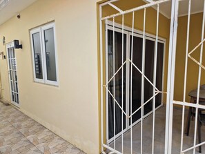 Ein Gebäude mit beige farbenem Mauerwerk, einem verschlossenen Eingangsbereich und einer gefliesten Terrasse.