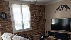 Ein modernes Wohnzimmer mit einer Couch, einem Flachbildfernseher und einer Steinwand.