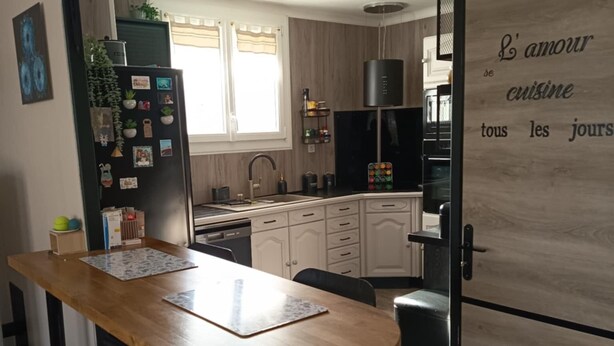 Eine moderne Küche mit einem Holztisch, schwarzen Schränken und einem schwarzen Kühlschrank.