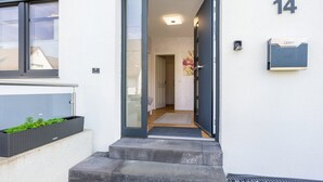 Une entrée moderne avec une porte en verre, une boîte aux lettres et le numéro 14 peint sur le mur.