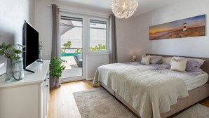 Une chambre à coucher avec un lit, une télévision, un lustre et un tableau représentant un phare.