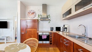 Une cuisine de taille réduite, dotée de meubles en bois, d’une cuisinière en acier inoxydable, d’un four à micro-ondes et d’un évier.