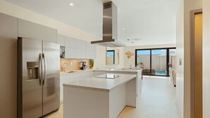 Una cocina moderna con una isla central, electrodomésticos de acero inoxidable y vistas a una zona de piscina.