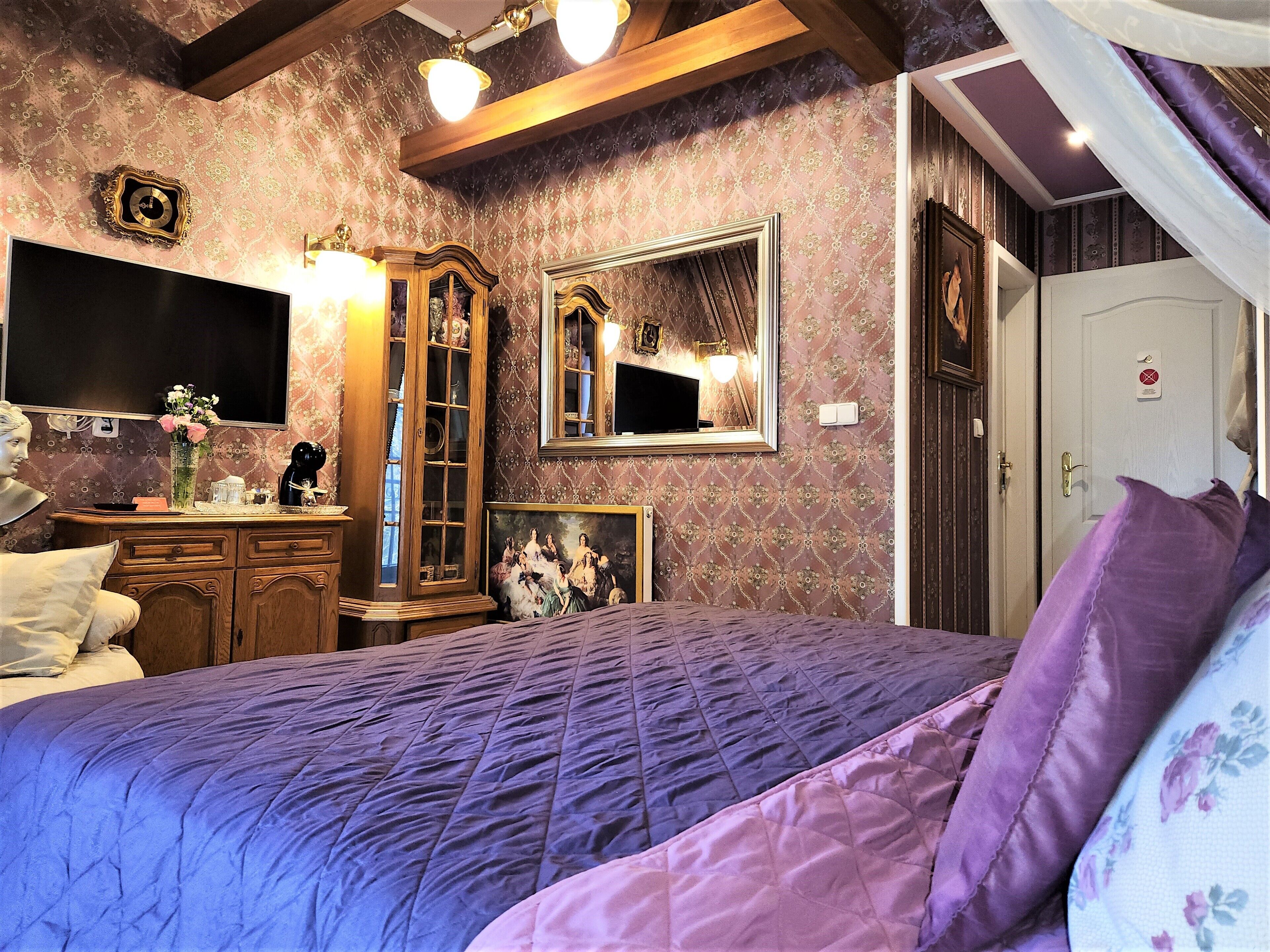 Un dormitorio con una cama grande, un aparador, un espejo y un televisor en la pared.