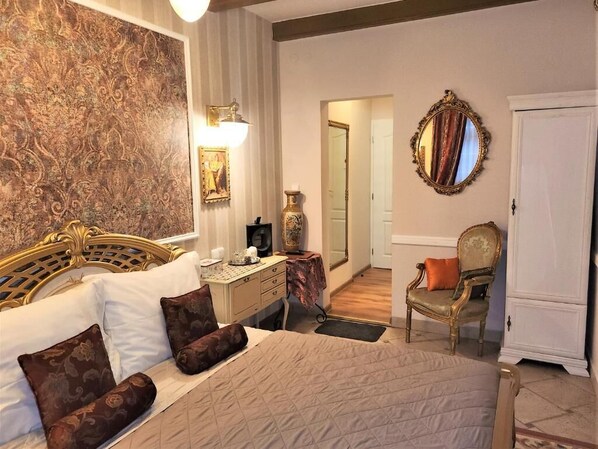 A hotel room with a large bed, a nightstand, a chair, a mirror, and a door. - REZIDENCE ZÁMEČEK - BOUTIQUE HOTEL (Františkovy Lázně)