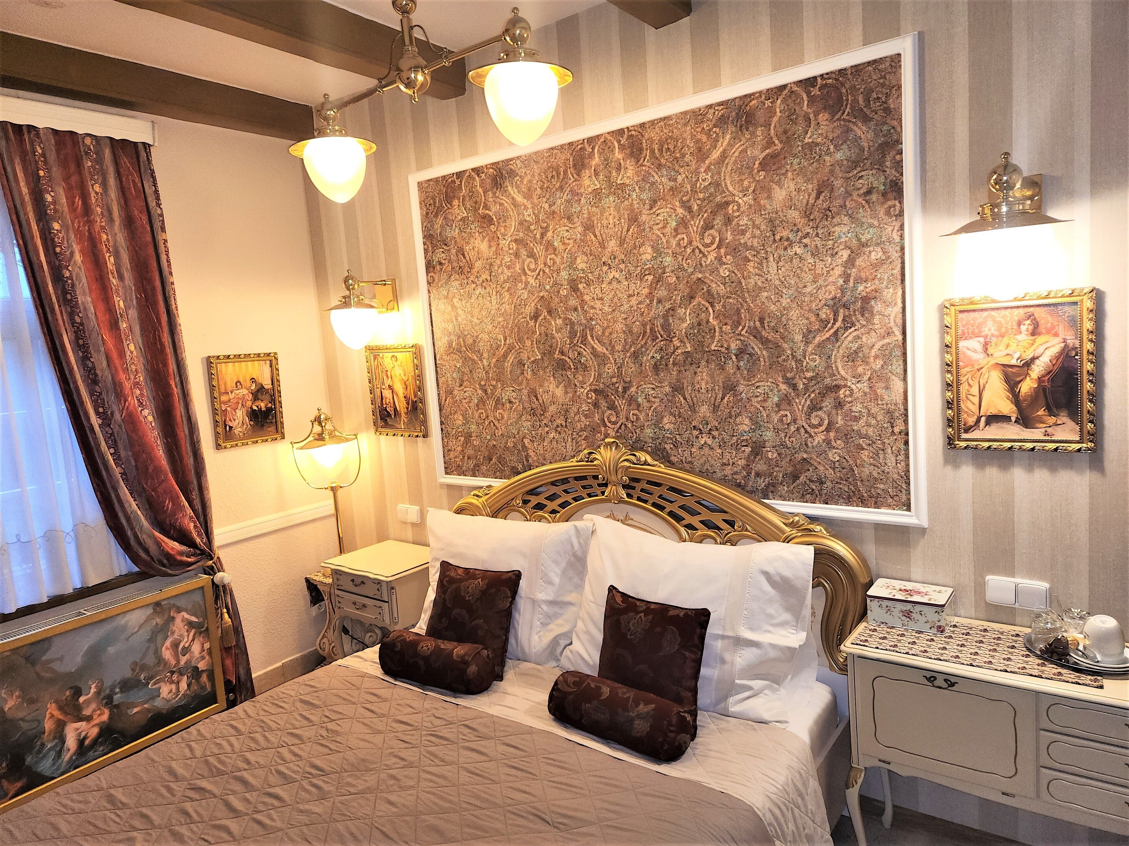Una camera da letto classica con un letto grande, una testiera decorata e un quadro astratto di grandi dimensioni appeso alla parete.
