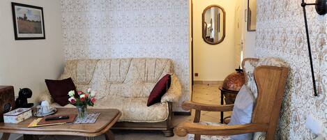 A cozy living room with a patterned sofa, a wooden coffee table, and a vintage armchair.
