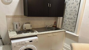 Une cuisine compacte équipée d’un lave-linge, d’une bouilloire, d’un grille-pain et d’un évier.