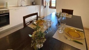 A modern kitchen with white cabinets, a wooden ceiling, and a dining area with a table set for four. - pieve san biagio (Macerata)