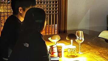 Una pareja sentada en una mesa con una vela, una copa de vino y una lámpara.