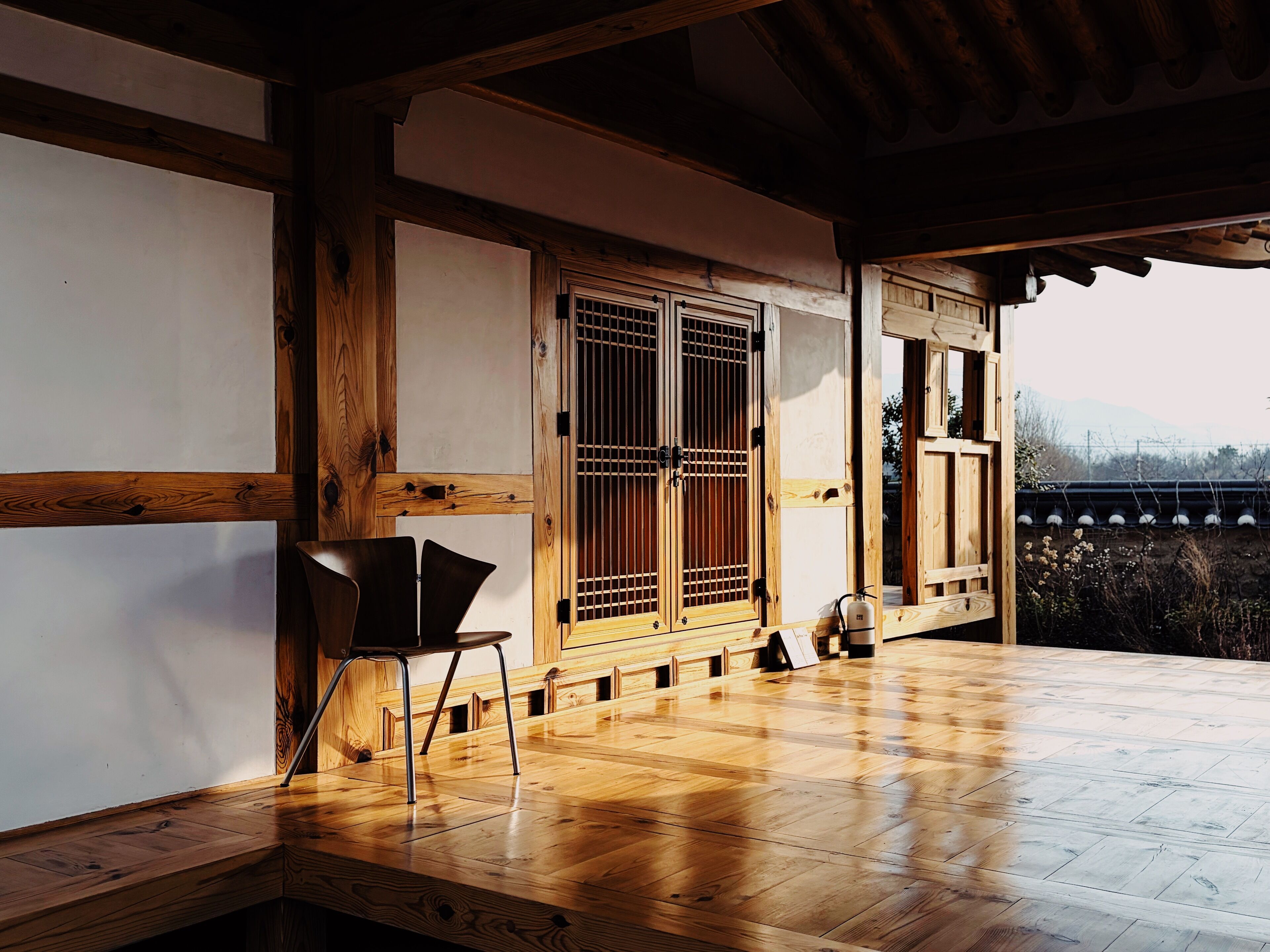 A traditional wooden room with tatami flooring, a sliding door, and a view of mountains.