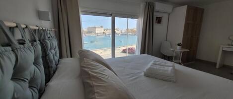 Una habitación de hotel con una cama, un escritorio, una silla y vista al mar.
