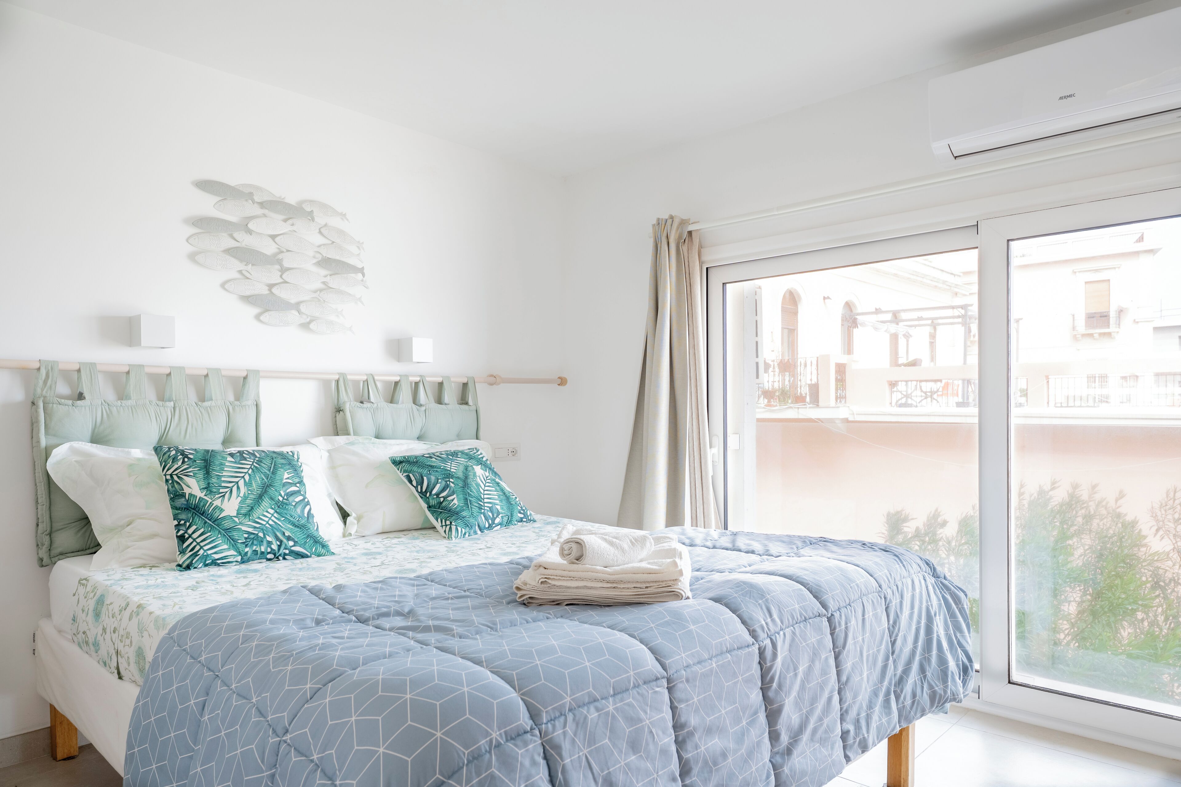 A bedroom with a bed, pillows, a window, and a wall decoration.