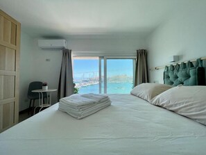 Une chambre d’hôtel avec un lit, une vue sur la mer et une petite table avec une chaise.