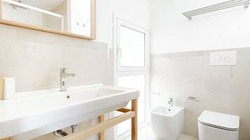 A modern bathroom with a white sink, mirror, and toilet.