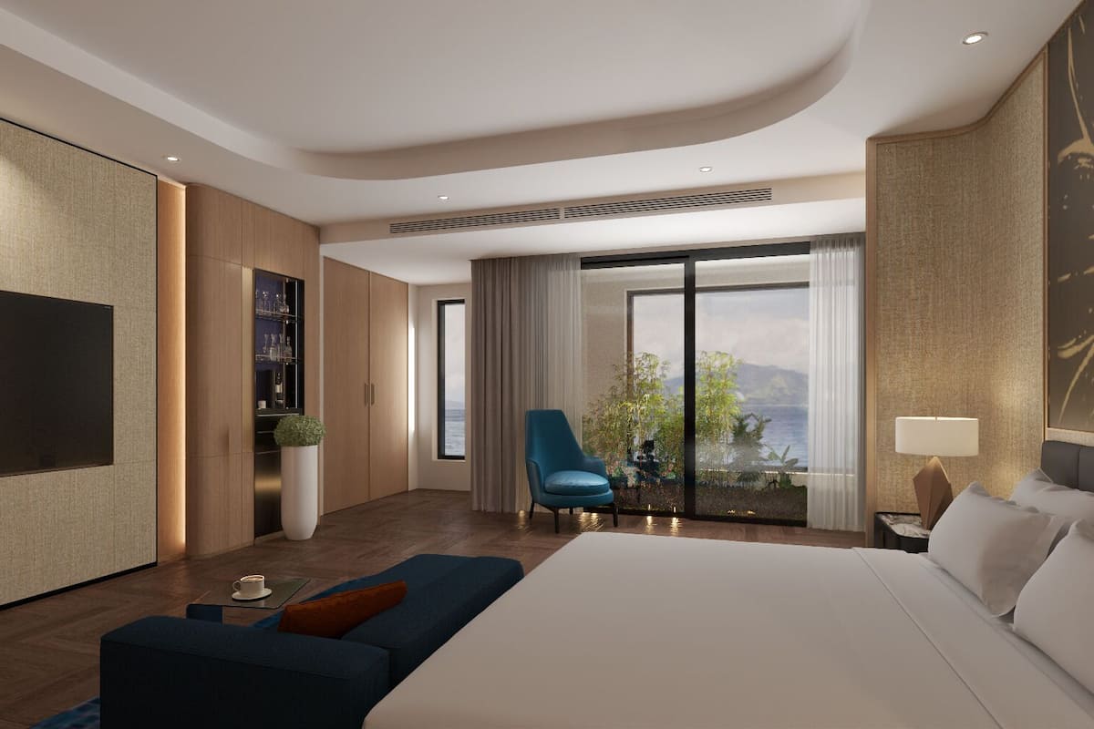 Une chambre d’hôtel moderne avec un grand lit, un coin salon comprenant un canapé bleu, un fauteuil et un téléviseur.