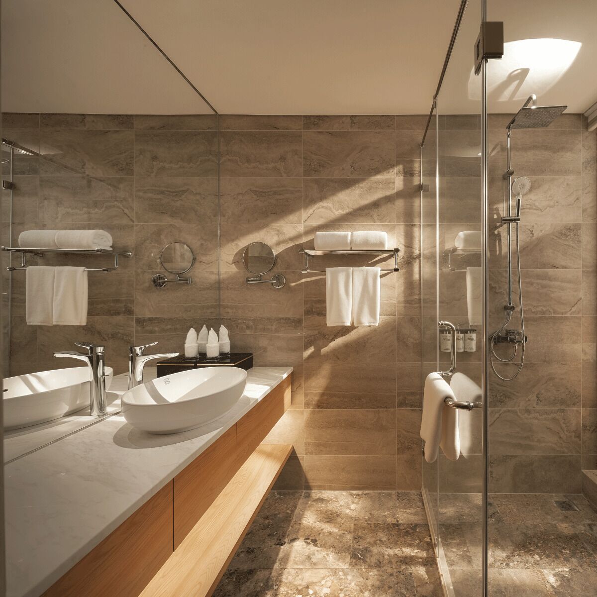 Een moderne badkamer met een groot wastafelmeubel, twee spiegels, een douchecabine van glas en marmeren wanden.