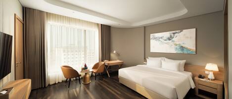 A hotel room with a bed, a desk, a chair, a TV, and a window with curtains.