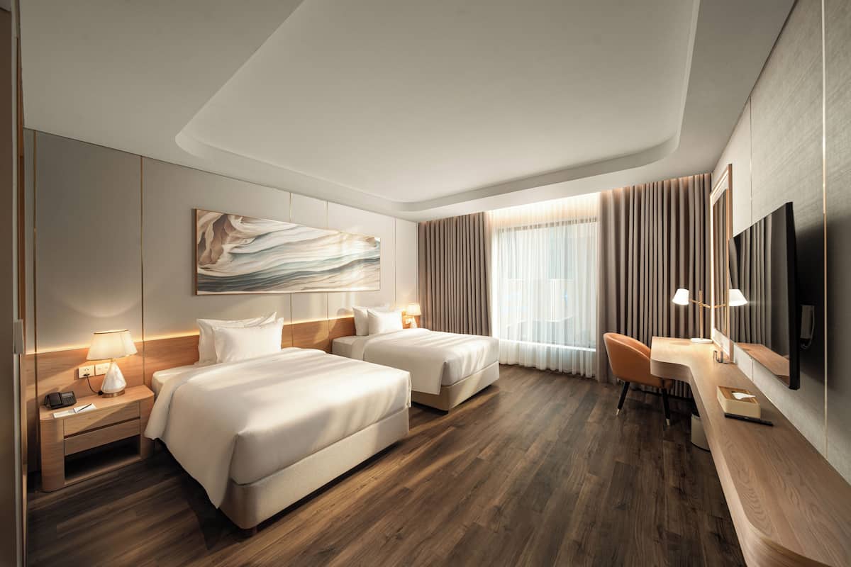 Une chambre d’hôtel avec deux lits, un bureau, une chaise, une télévision et un grand tableau abstrait.
