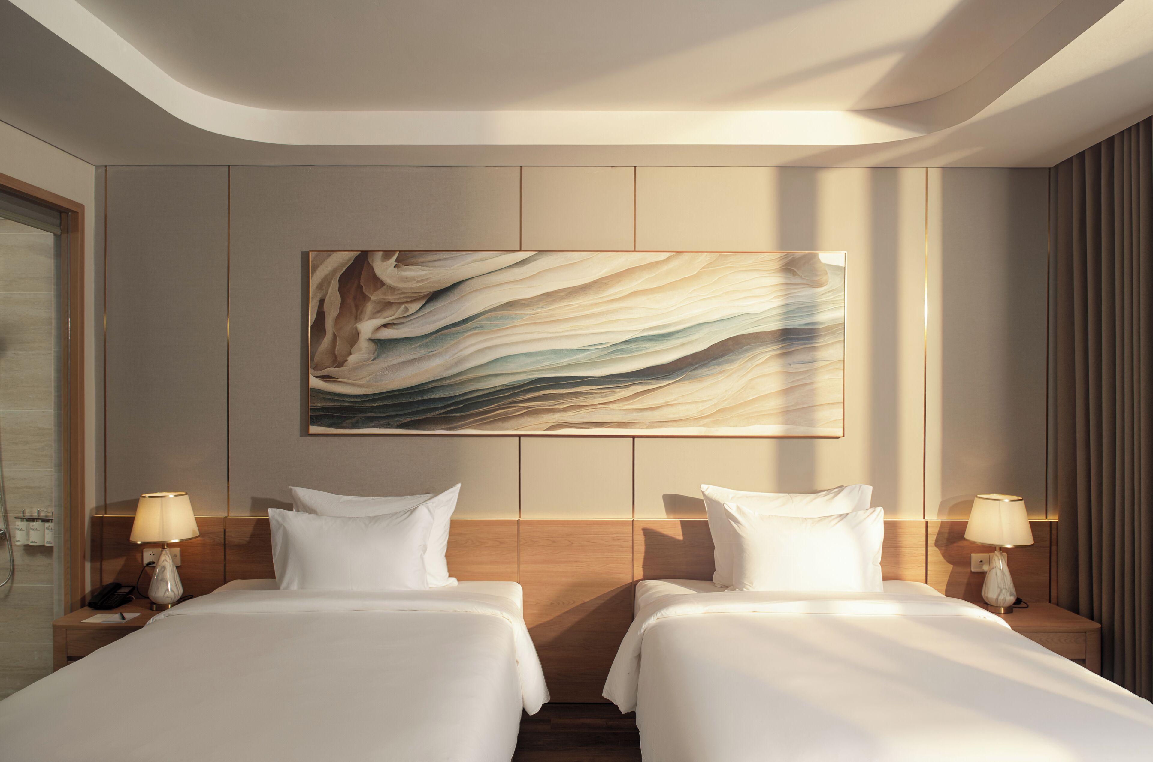 Une chambre d’hôtel avec deux lits, une grande peinture abstraite et une tête de lit en bois.